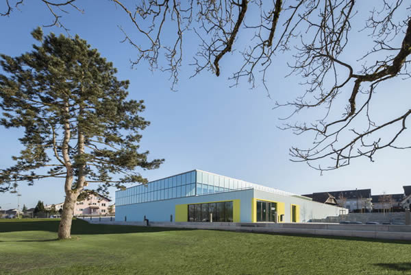 The threefold sports hall in the Swiss township of Strengelbach is optically divided in two volumes. The building has a captivating ornamental base and a glass top of light diffusing OKALUX K insulating glass with capillary inserts.