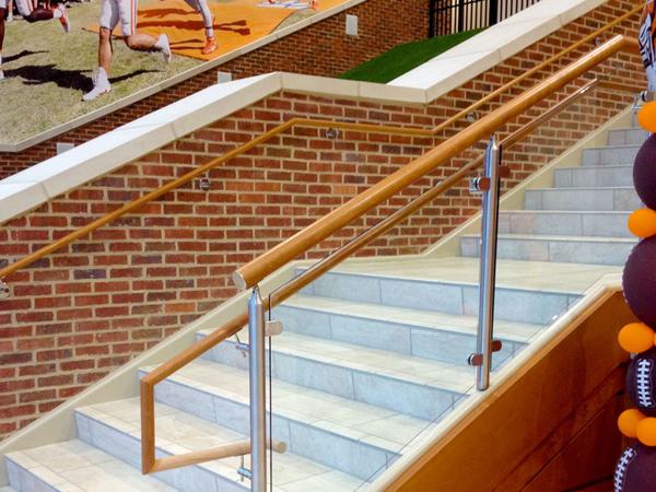Top mounted Monaco railing with wood top cap and handrail utilized the D-shaped clamp to secture glass infill