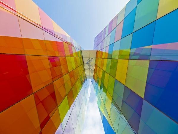 Arranged in a harlequin pattern, the glazed panels − in shades of red, yellow, green, blue and white − cover the entirety of the structure in a multi-colored façade. Image © Tecnoglass