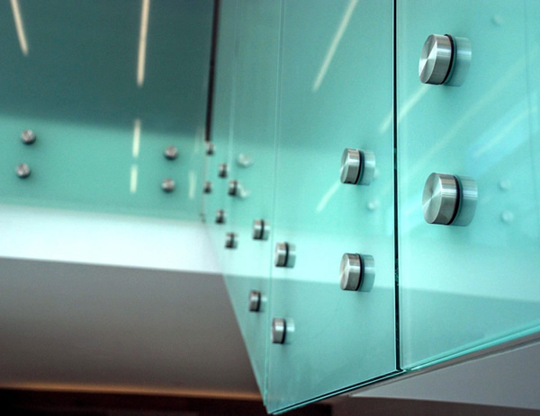 Frosted laminated glass was used on the lobby staircase. Stainless steel “buttons” pass through the glass and are bolted into the fascia for a clean, minimalist look.