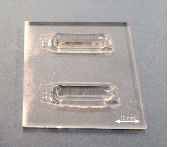 Fig. 2: Photography of printed specimen. Two test specimens were printed on each 50x50 mm fused silica substrate, which was cut in half using a laser cutting process ©Sleiman.