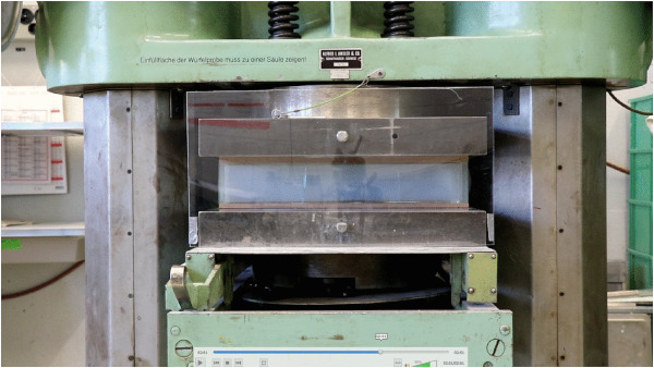 Fig. 6. Test of compression strength. The brick is placed between two pieces of plywood to redistribute forces and minimize irregularities of the surface for the experiment.