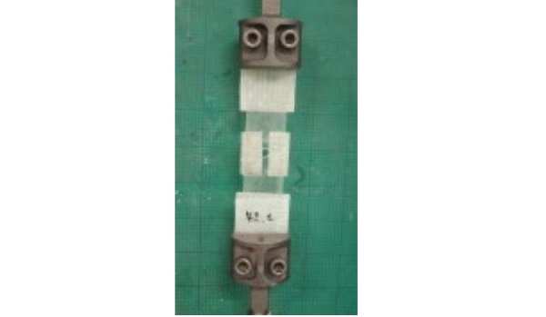 Fig. 6: GFRP reinforced open hole test specimen (note: GFRP strips were also used to reinforce the ends of test specimen as means of eliminating possible failure at the ends of the test specimen)