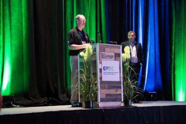 Jeff Smith, at the podium, expresses his gratitude for receiving the 2023 Glass Manufacturing Excellence Award while GMIC president Scott Cooper looks on. Credit: ACerS