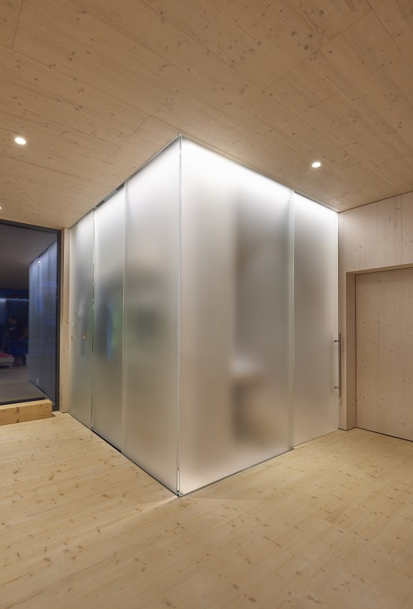 The glassy room-in-room feature shines in silky white – it separates the bathroom and coatrack from the entrance and living area.