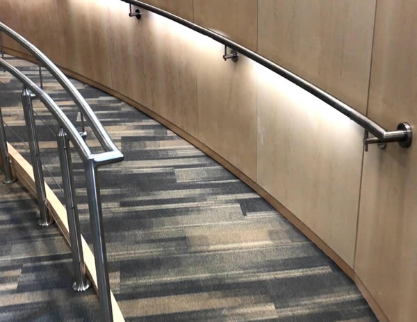 Interior ramp features Casino cable railing with post mounted handrail, and wall mounted handrail incorporating LED lighting.