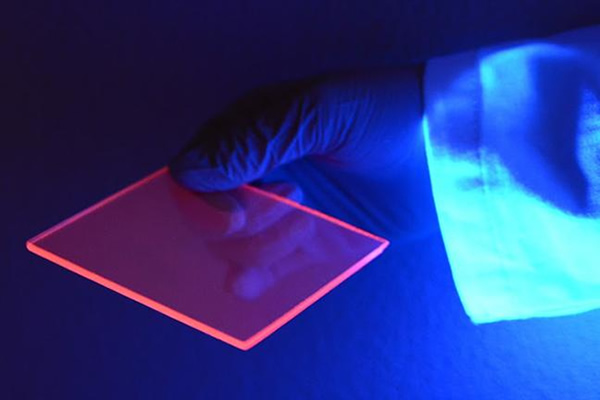 While most of the light concentrated to the edge of the silicon-based luminescent solar concentrator is actually invisible, we can better see the concentration effect by the naked eye when the slab is illuminated by a “black light” which is composed of mostly ultraviolet wavelengths. Credit: Uwe Kortshagen, College of Science and Engineering