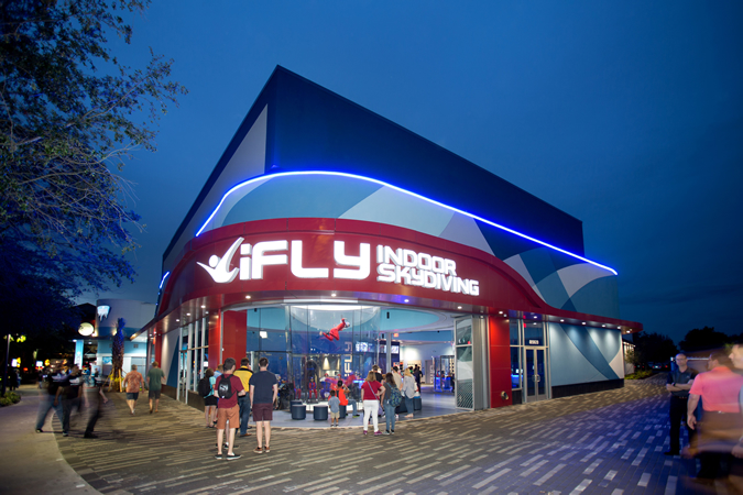 Spectators gathering around a flying person in iFly's flying tunnel.