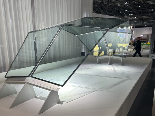 Close-up of four glass panels meeting at a central metal connection, with diagonal patterns visible through the glass