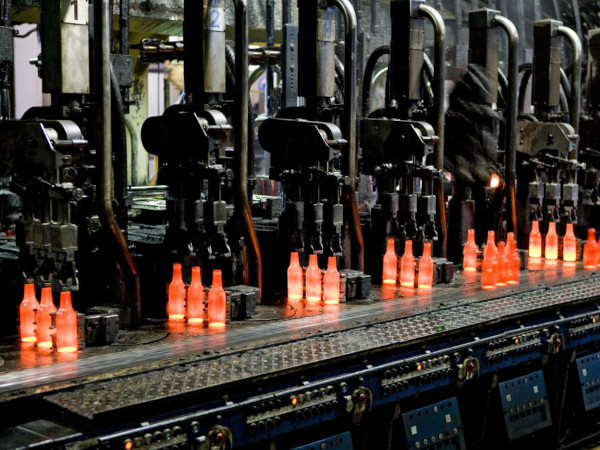 Red-hot glass bottles right after being moulded: in the IS machine the molten glass receives its final shape before the containers are fed to the annealing lehr. Photo: Bundesverband Glasindustrie e.V. (BV Glas)