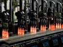 Red-hot glass bottles right after being moulded: in the IS machine the molten glass receives its final shape before the containers are fed to the annealing lehr. Photo: Bundesverband Glasindustrie e.V. (BV Glas)