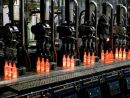 Red-hot glass bottles right after being moulded: in the IS machine the molten glass receives its final shape before the containers are fed to the annealing lehr. Photo: Bundesverband Glasindustrie e.V. (BV Glas)