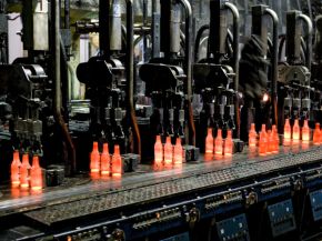 Red-hot glass bottles right after being moulded: in the IS machine the molten glass receives its final shape before the containers are fed to the annealing lehr. Photo: Bundesverband Glasindustrie e.V. (BV Glas)