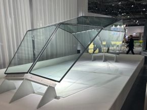 Close-up of four glass panels meeting at a central metal connection, with diagonal patterns visible through the glass