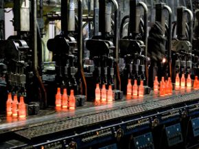 Red-hot glass bottles right after being moulded: in the IS machine the molten glass receives its final shape before the containers are fed to the annealing lehr. Photo: Bundesverband Glasindustrie e.V. (BV Glas)