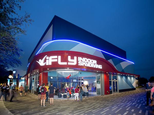 Spectators gathering around a flying person in iFly's flying tunnel.