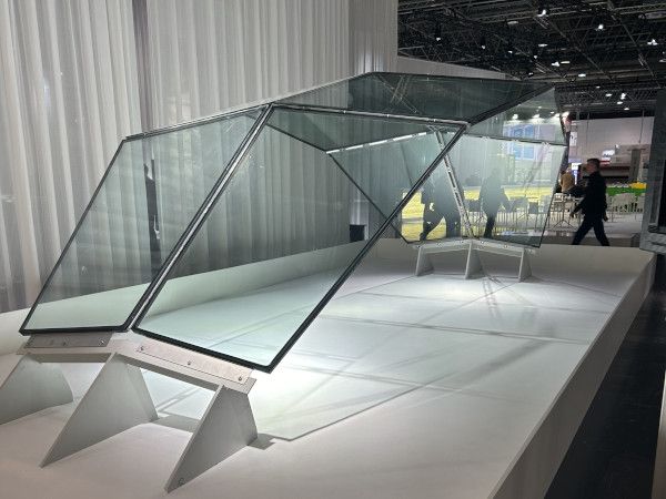 Close-up of four glass panels meeting at a central metal connection, with diagonal patterns visible through the glass
