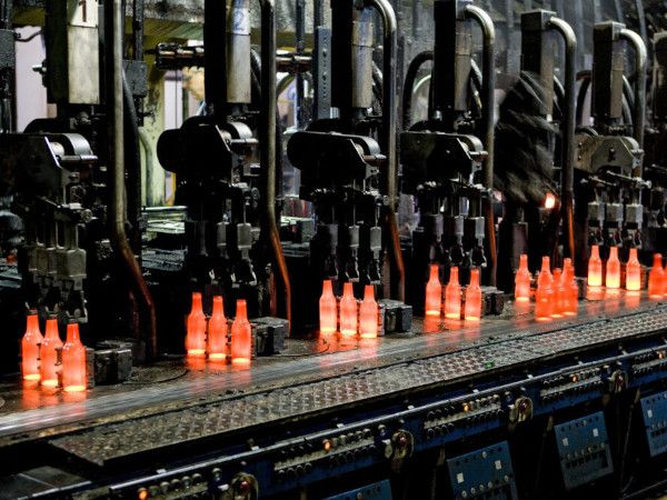 Red-hot glass bottles right after being moulded: in the IS machine the molten glass receives its final shape before the containers are fed to the annealing lehr. Photo: Bundesverband Glasindustrie e.V. (BV Glas)